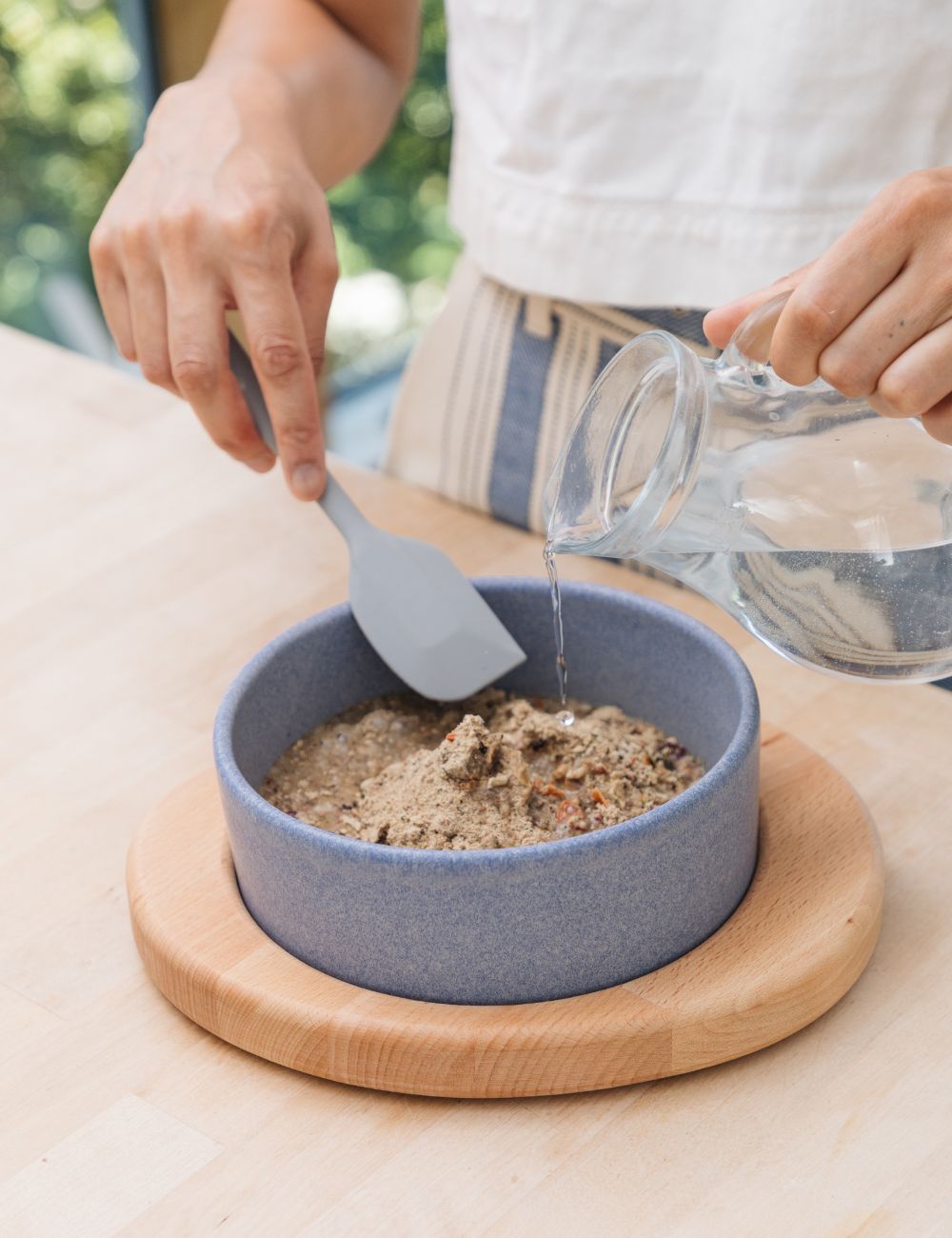 Wasser aus einem Krug, das in einen Napf geleert wird.