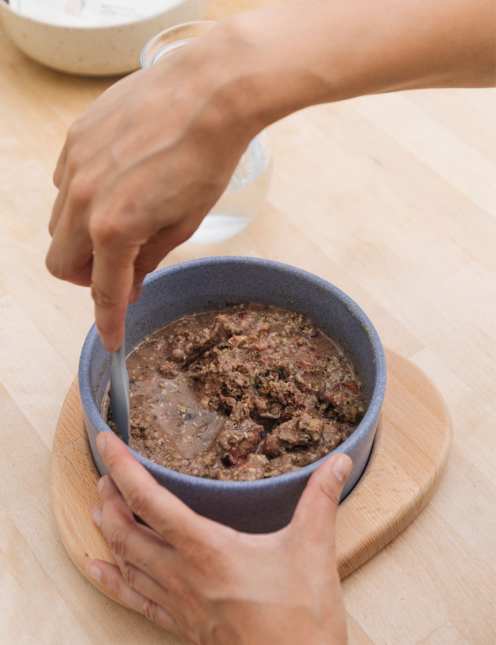 Futter, welches frisch mit Wasser in einem blauen Keramiknapf angerührt wird
